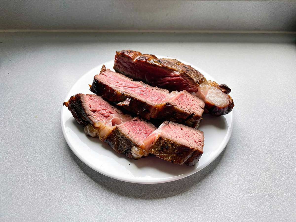 3 plakken ribeye, sommige met wat vet, liggen op een bord.