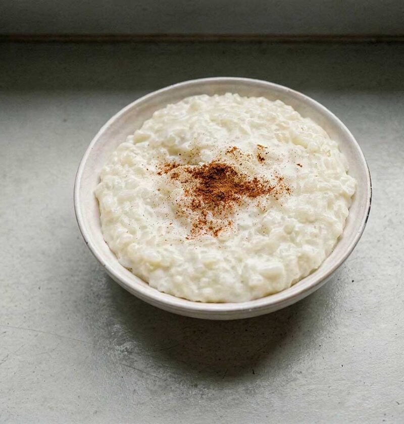 Een schaal rijstepap met een snufje kaneelpoeder.