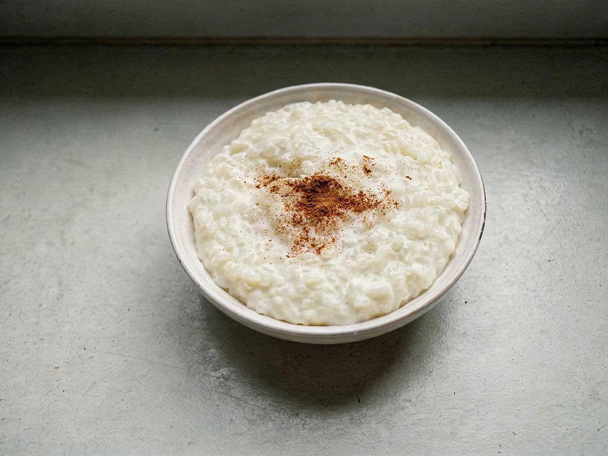 Een schaal rijstepap met een snufje kaneelpoeder.