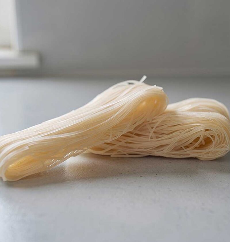 2 bundels droge rijstnoedels op een werkblad van een keuken.