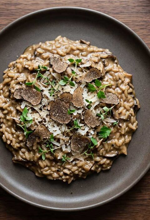 Een donker bord met daarop een overgebleven portie risotto.