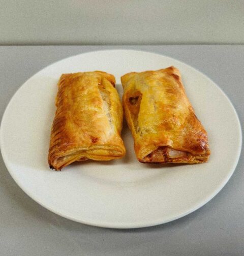2 op saucijzenbroodjes op een wit bordje, zojuist opgewarmd.