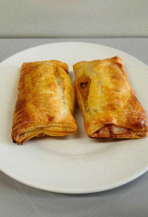 2 op saucijzenbroodjes op een wit bordje, zojuist opgewarmd.