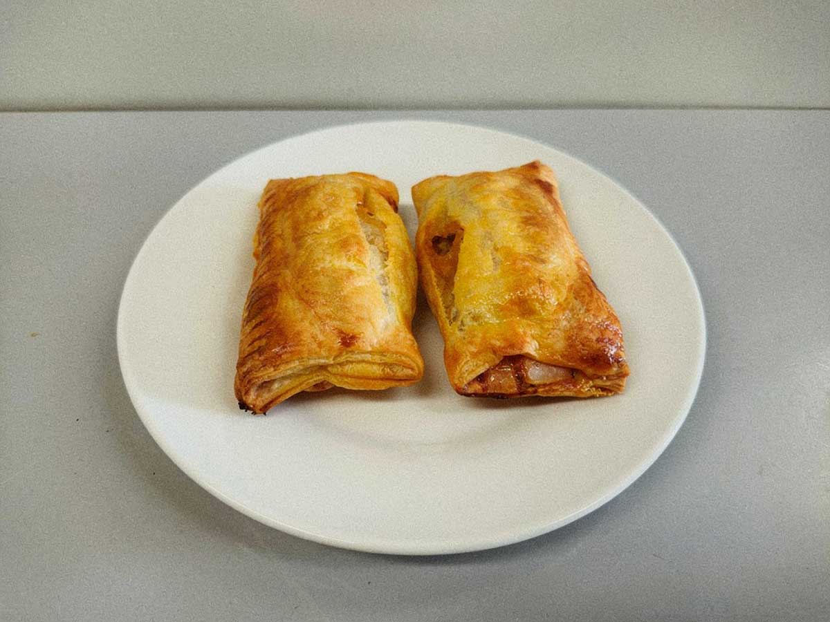 2 op saucijzenbroodjes op een wit bordje, zojuist opgewarmd.