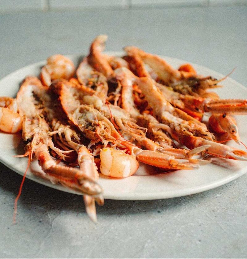 Een schaal met gehalveerde en gebakken scampi.