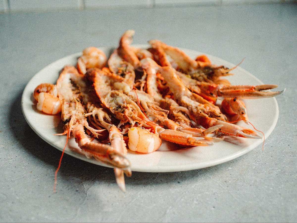Een schaal met gehalveerde en gebakken scampi.