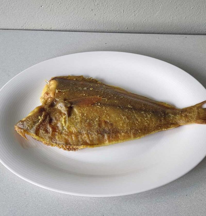 Een gebakken scharfilet op een wit ovaal bord.