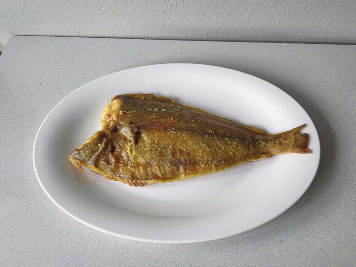 Een gebakken scharfilet op een wit ovaal bord.