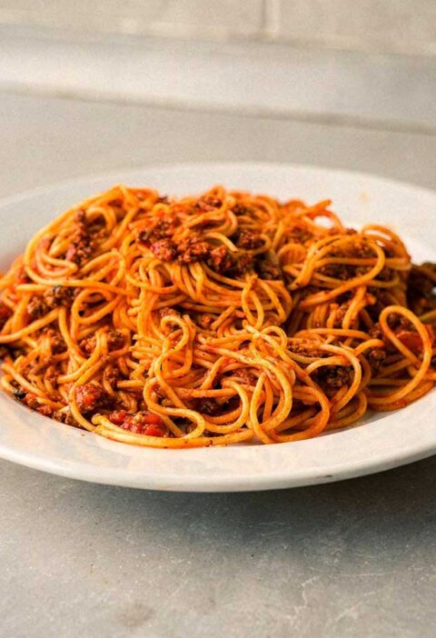 Een bord vol spaghetti met een tomatensaus.