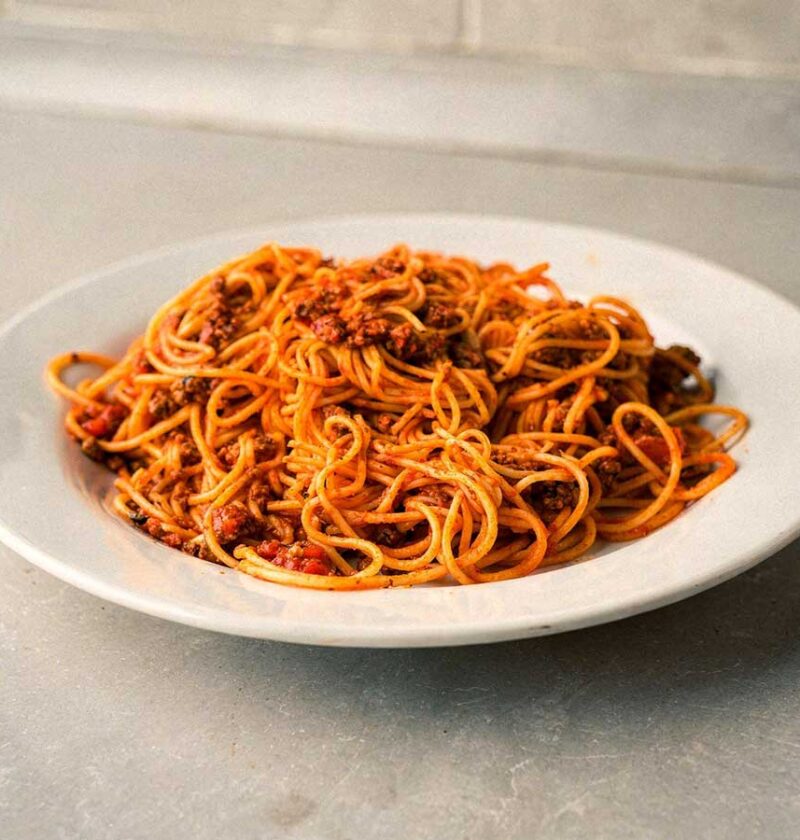 Een bord vol spaghetti met een tomatensaus.