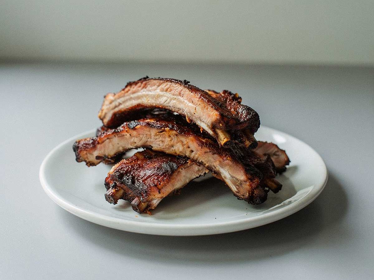 4 gebakken spareribs (stukken) op een wit bordje.