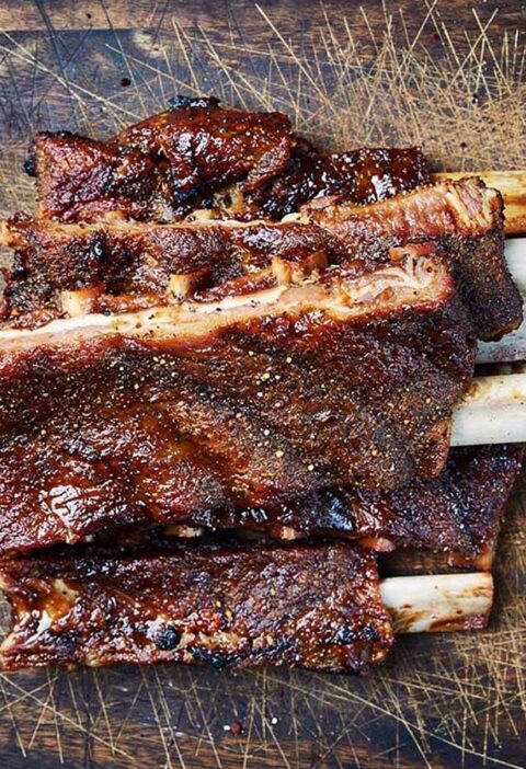 Opgewarmde spereribs op een houten ondergrond.