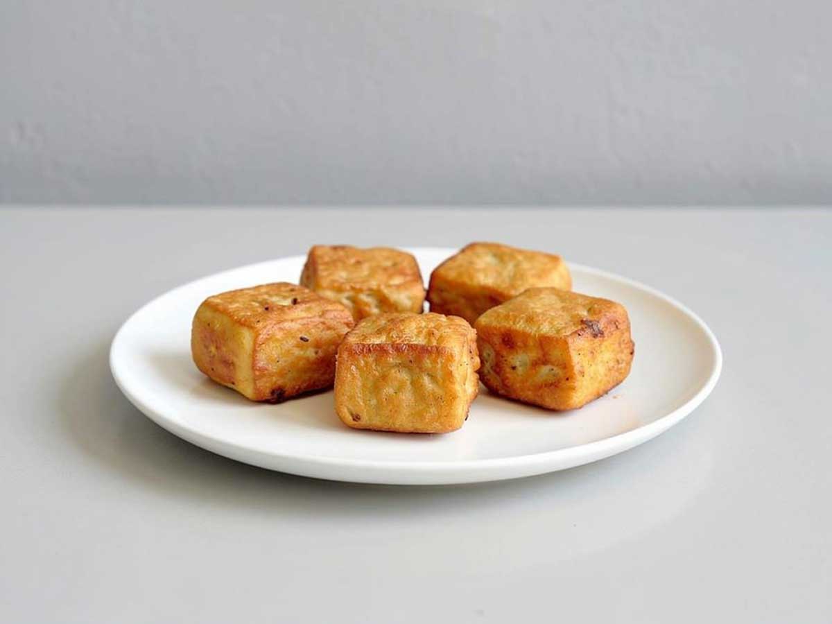 5 stukjes tahu goreng op een wit bordje.
