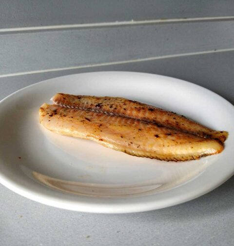Een gebakken tilapiafilet op een wit bordje.