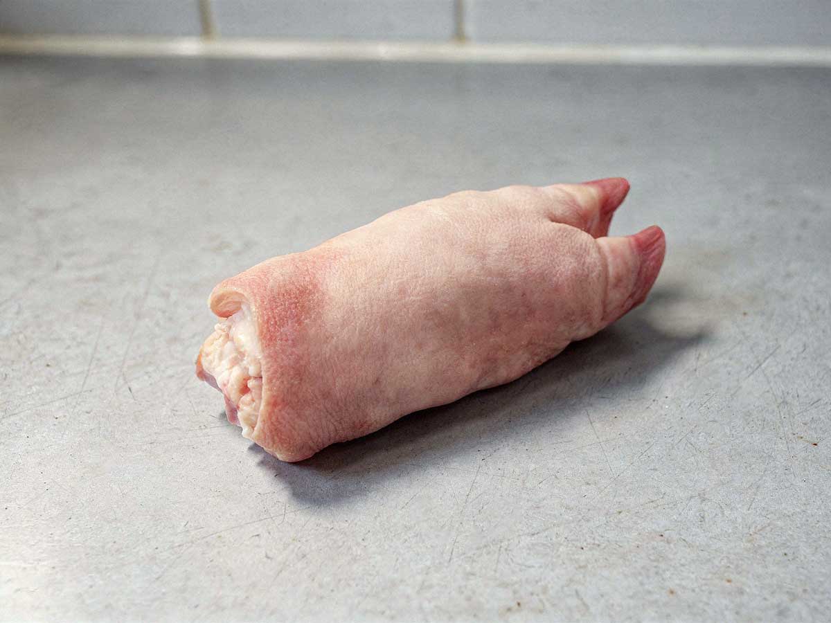 Een rauw varkenspoot ligt op een aanrecht, klaar om gekookt te worden.