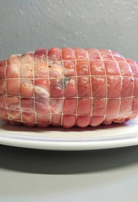 Een hele vrakensrollade, in een net, maar nog niet gebraden.