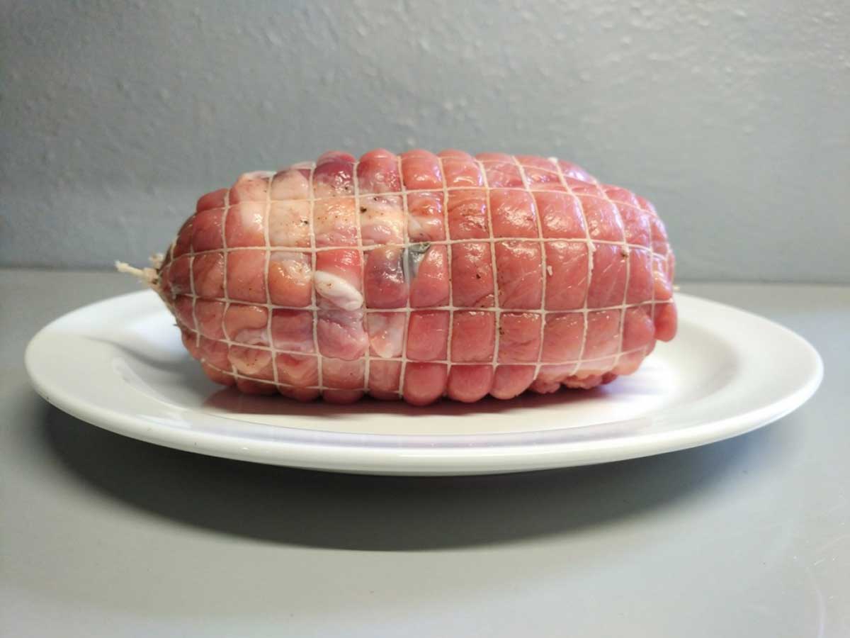 Een hele vrakensrollade, in een net, maar nog niet gebraden.