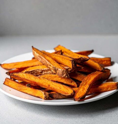 Een bordje met zoete aardappel friet, gebakken in een oven.