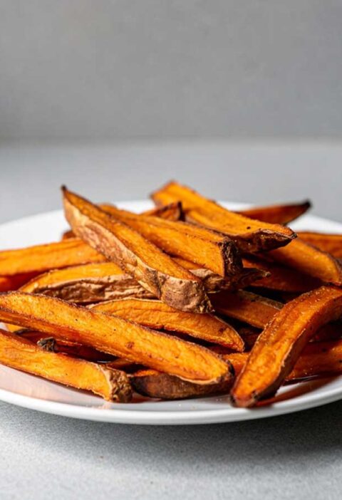 Een bordje met zoete aardappel friet, gebakken in een oven.