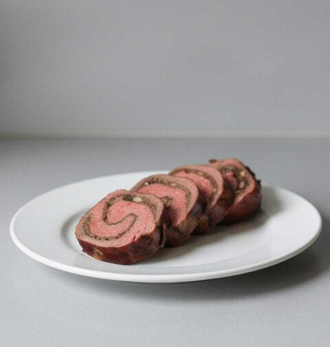 4 plakken van een gevulde bavette rollade op een witte schaal.