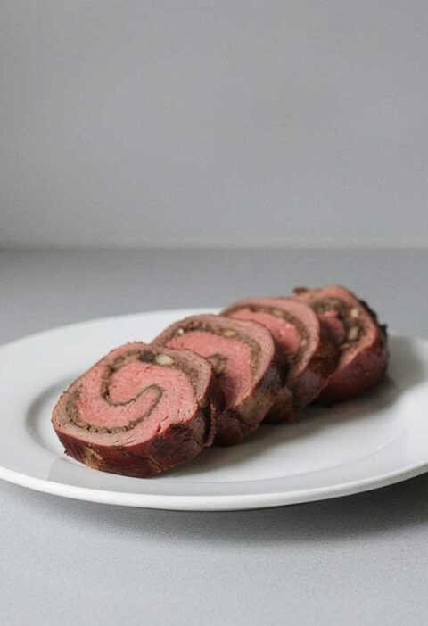 4 plakken van een gevulde bavette rollade op een witte schaal.
