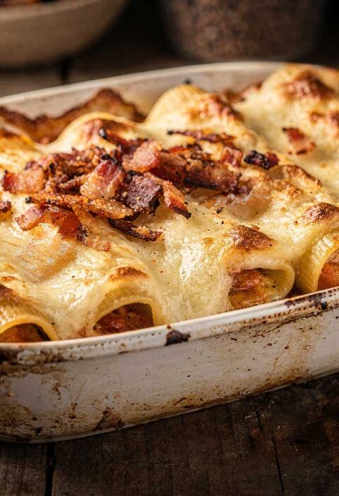 Zelfgemaakte cannelloni met bechamelsaus en spekjes in een witte ovenschaal