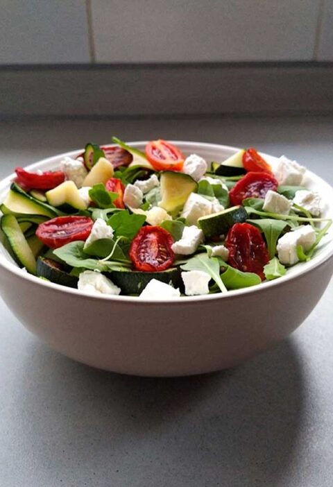 Een schaaltje met courgettesalade met tomaatjes en feta.