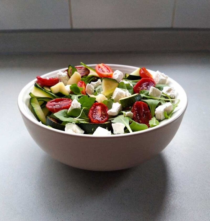Een schaaltje met courgettesalade met tomaatjes en feta.