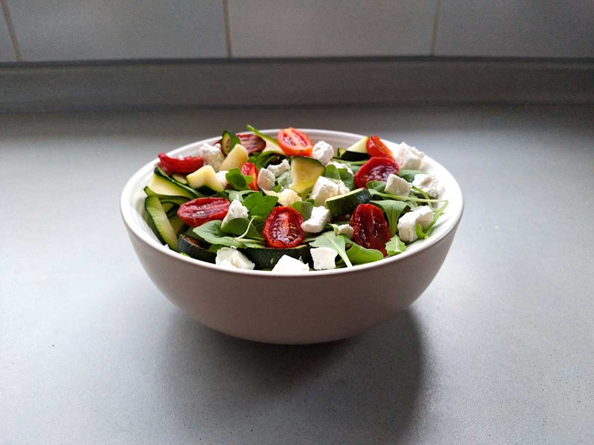 Een schaaltje met courgettesalade met tomaatjes en feta.