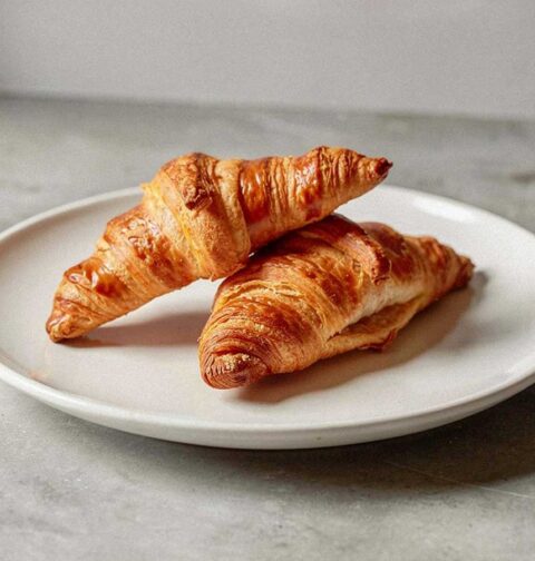 2 vers gebakken croissants op een wit bordje.