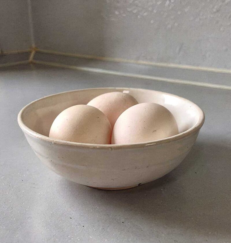 Een wit schaaltje met daarin 3 eendeneieren die straks gekookt gaan worden.