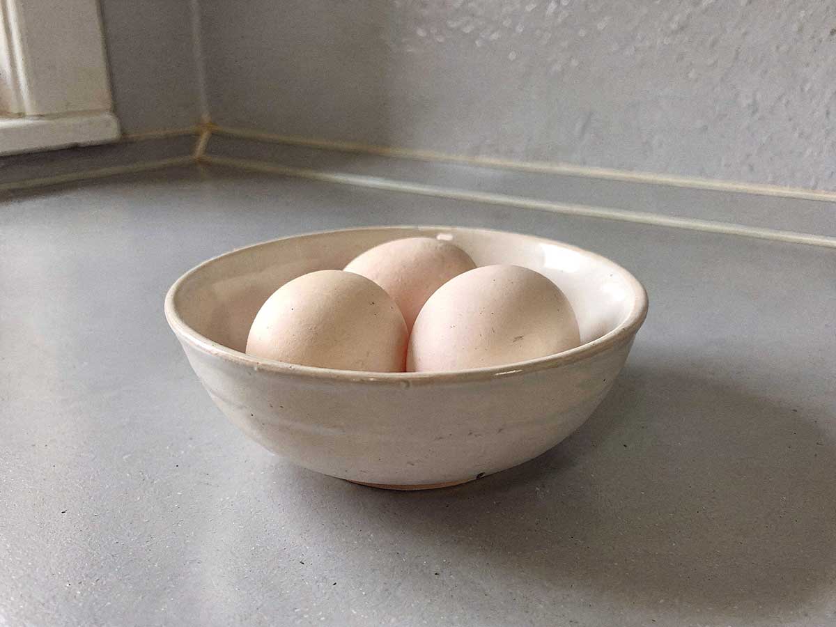 Een wit schaaltje met daarin 3 eendeneieren die straks gekookt gaan worden.