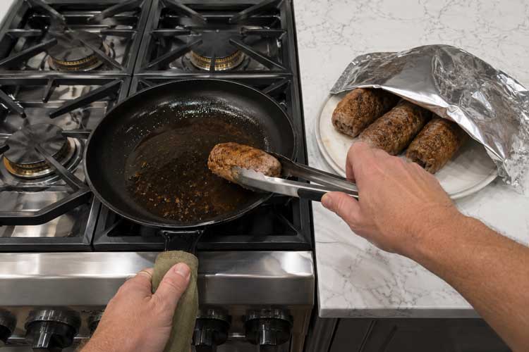 Haal de rundervinken uit de pan en laat ze 2 tot 3 minuten rusten op een bord onder aluminiumfolie