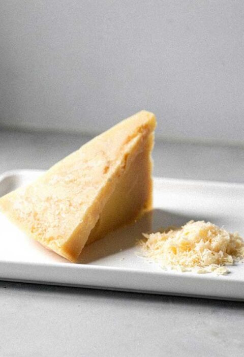 Een stuk Parmezaanse kaas waarvan een beetje is geraspt.