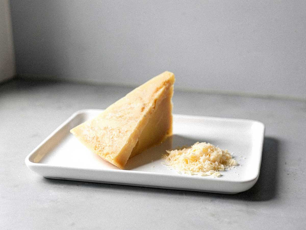 Een stuk Parmezaanse kaas waarvan een beetje is geraspt.