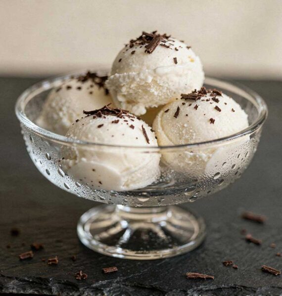 Glazen ijscoupe met vier bollen kokos roomijs en chocoladeschaafsel