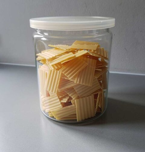 Een voorraadbus vol met kleine lasagnebladen (gedroogd), die gebruikt kunnen worden om te koken.
