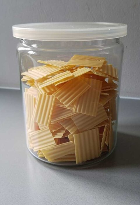 Een voorraadbus vol met kleine lasagnebladen (gedroogd), die gebruikt kunnen worden om te koken.