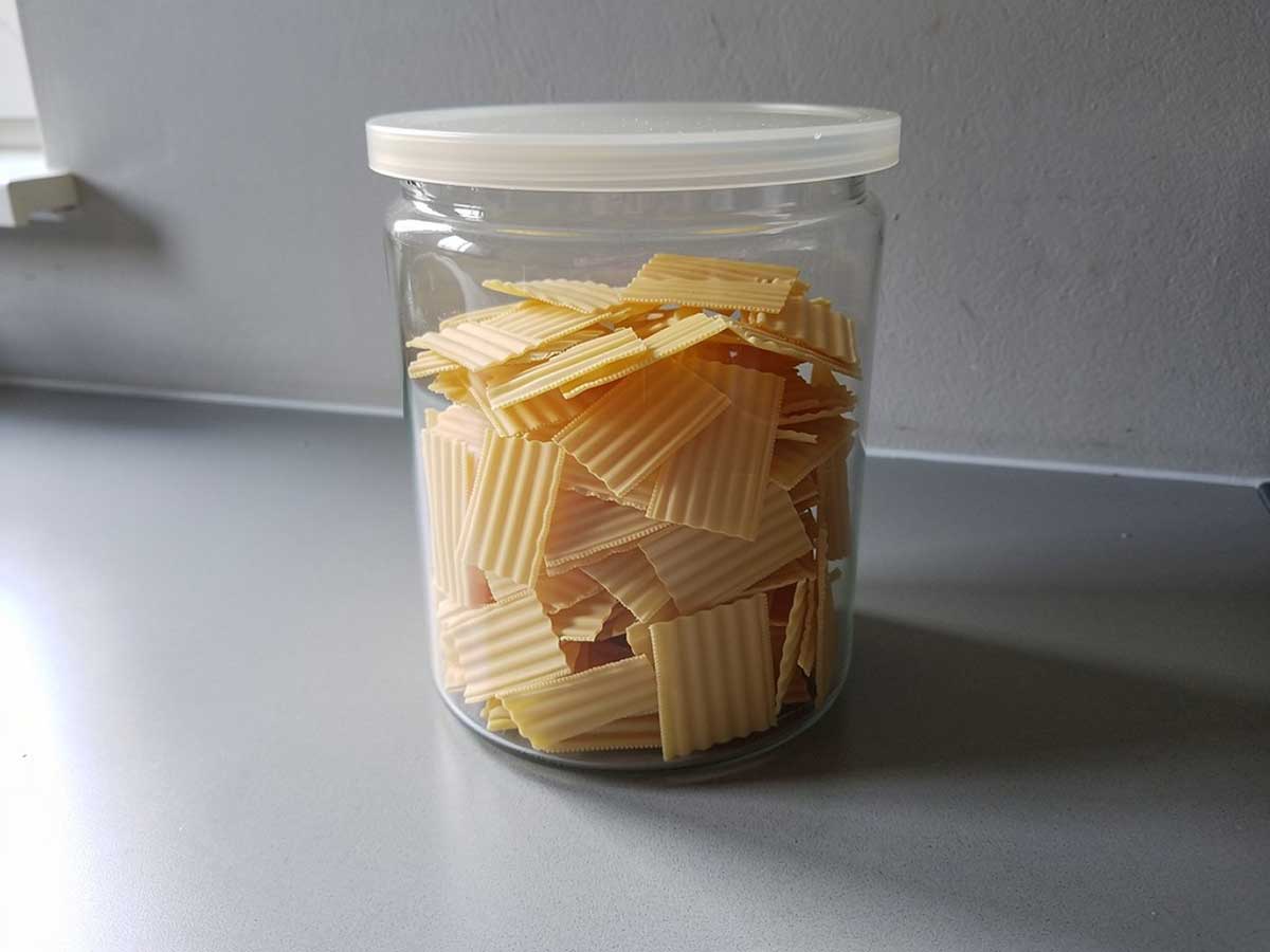 Een voorraadbus vol met kleine lasagnebladen (gedroogd), die gebruikt kunnen worden om te koken.