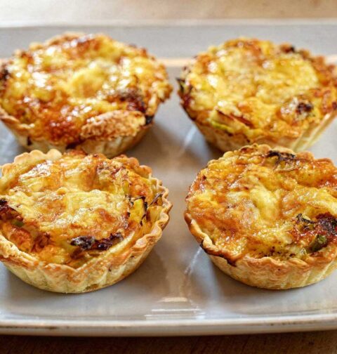 Vier mini quiches met parmaham en prei op een platte schaal