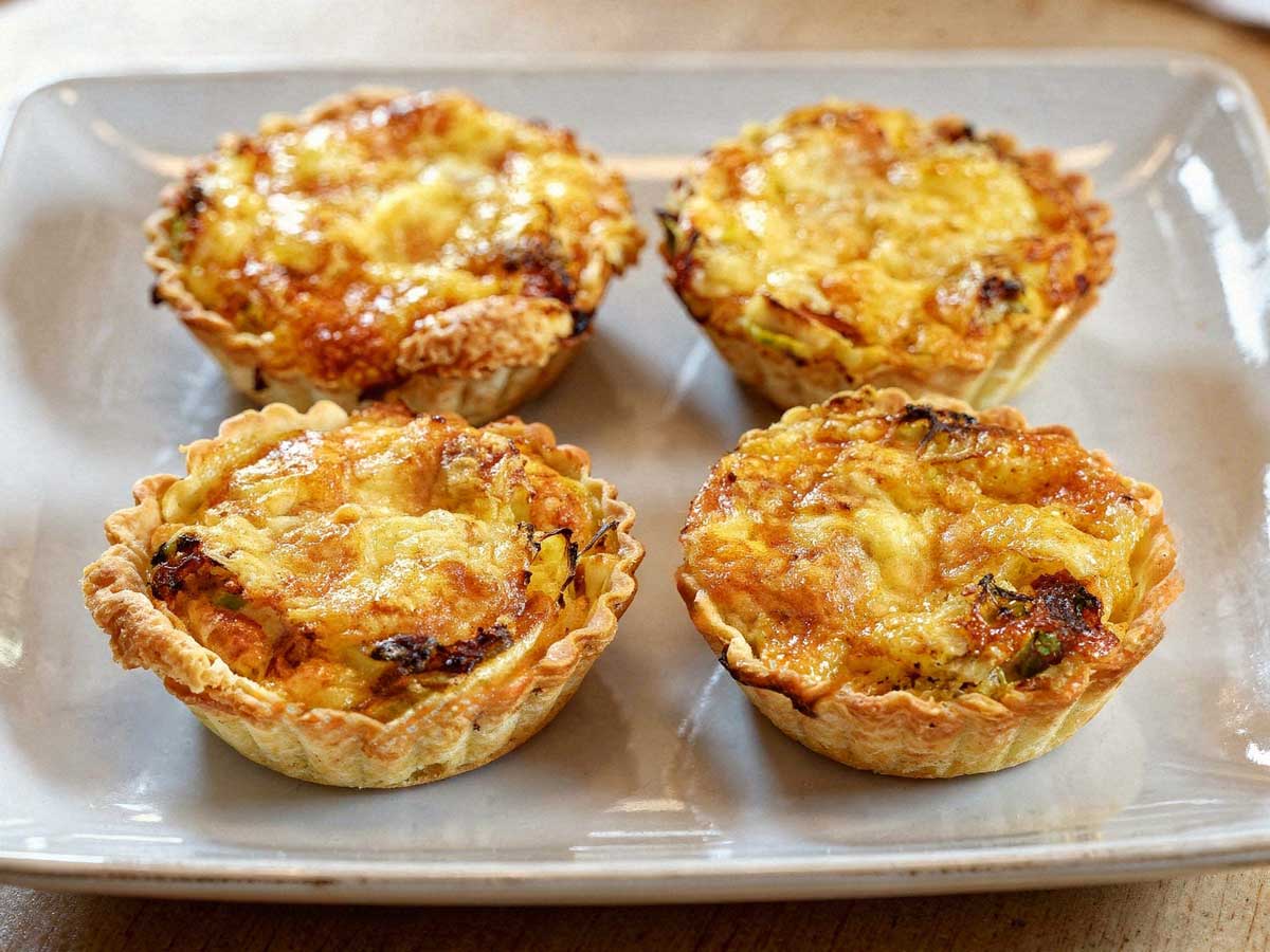 Vier mini quiches met parmaham en prei op een platte schaal