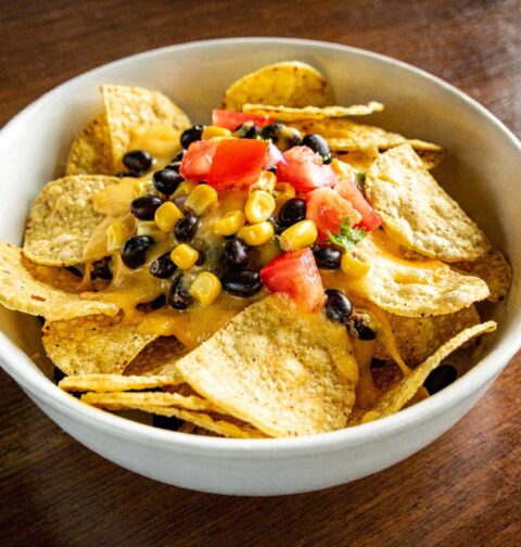 Nachos met kaas, maïs, tomaat en zwarte bonen.