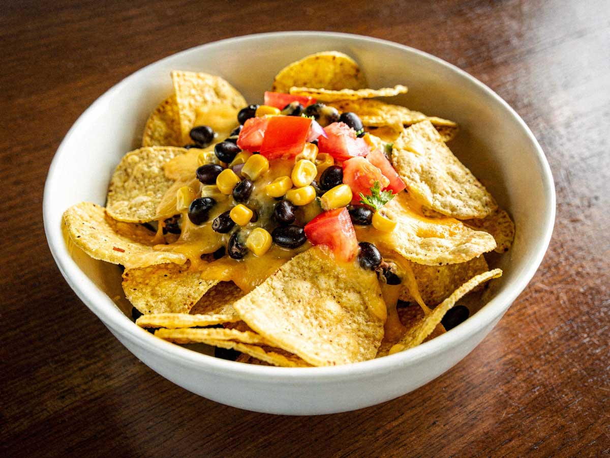 Nachos met kaas, maïs, tomaat en zwarte bonen.