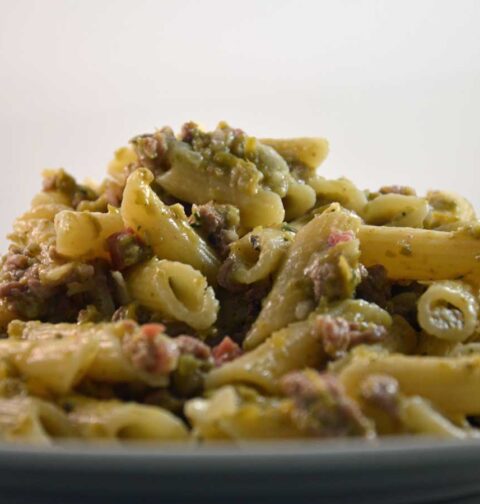 Een bord gekookte penne met een carbonarasaus.