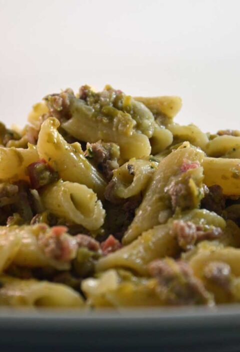 Een bord gekookte penne met een carbonarasaus.