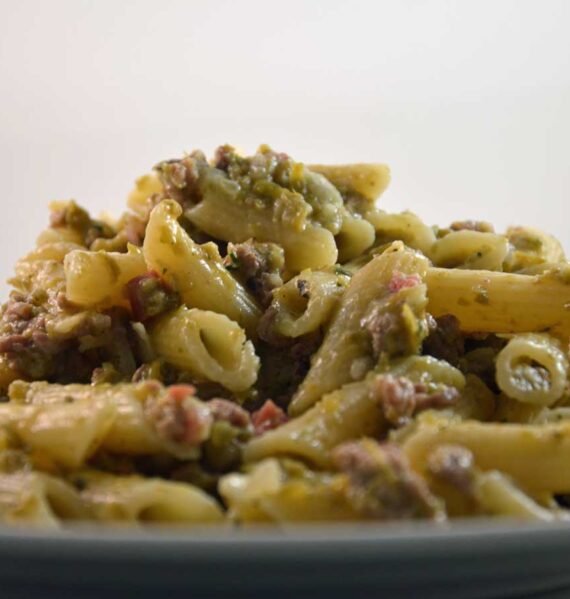 Een bord gekookte penne met een carbonarasaus.