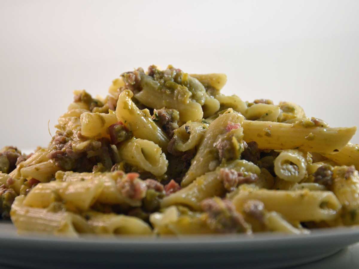 Een bord gekookte penne met een carbonarasaus.