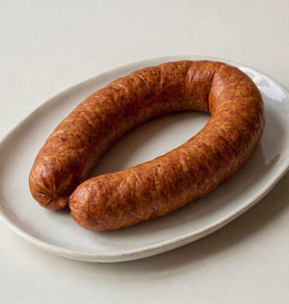 Een sappige, glanzende Hollandse rookworst op een plat wit bord zonder garnering.