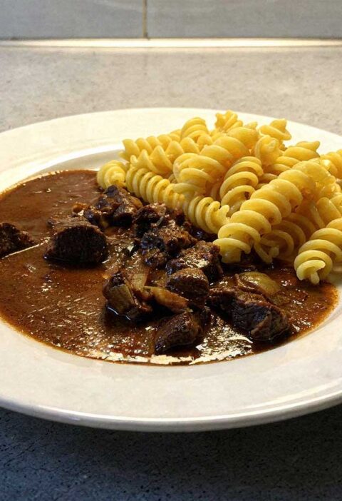 Een bord met fusilli en rundergoulash met chocolade.