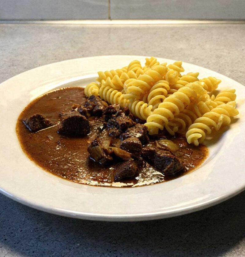 Een bord met fusilli en rundergoulash met chocolade.
